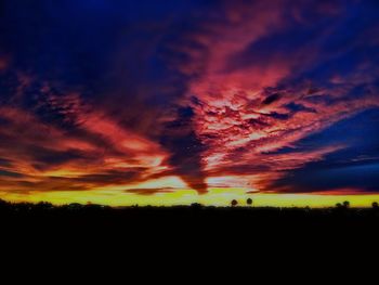 Silhouette landscape against dramatic sky during sunset