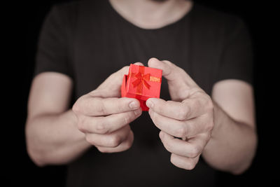 Close-up of hand holding red leaf against black background