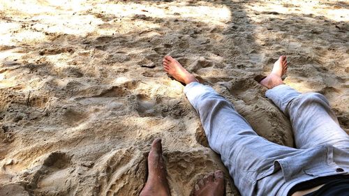 Low section of person relaxing on sand at beach