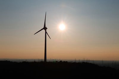 Silhouette windmill on field against sky during sunset