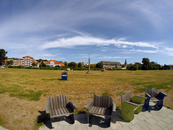 Scenic view of field by buildings against sky