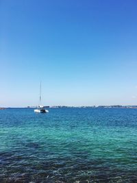Boat sailing in sea against clear blue sky