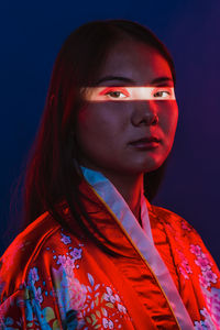 Portrait of young woman against black background