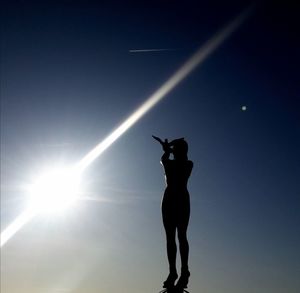 Low angle view of silhouette woman standing against sky