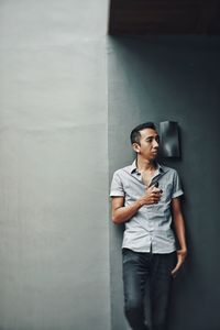 Young man looking at camera while standing against wall