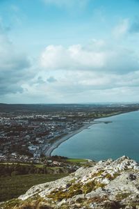 Aerial view of city by sea against sky