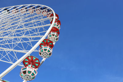 Low angle view of ferris wheel against clear blue sky