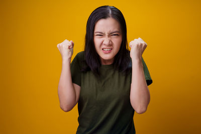 Beautiful young woman against yellow background