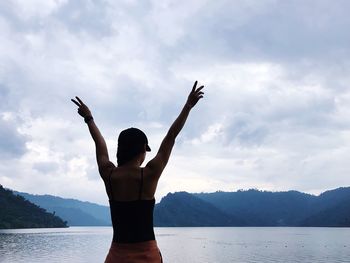 Rear view of woman standing by mountain against sky