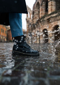 Low section of man standing on wet footpath