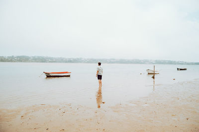 Rear view of man standing on beach against sky