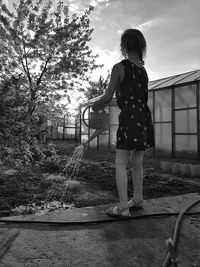 Rear view of woman standing by tree against sky