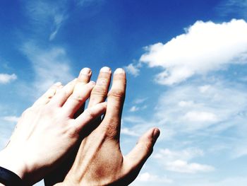 Low angle view of human hand against sky