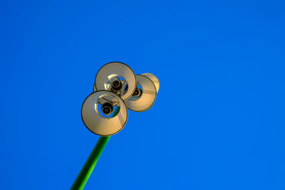 Low angle view of electric lamp against blue sky