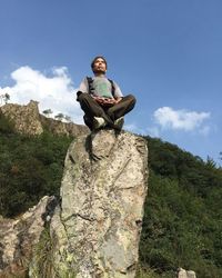 Low angle view of a man sitting on tree
