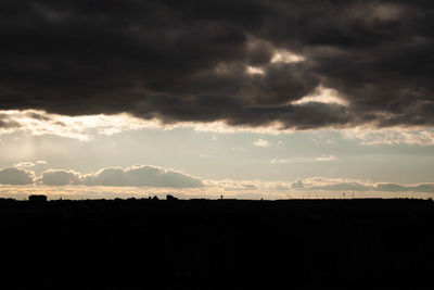 Silhouette landscape against dramatic sky during sunset