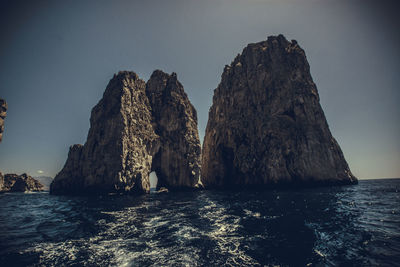 Rock formations in sea against clear sky