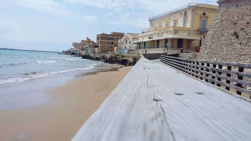 Surface level of beach against sky in city