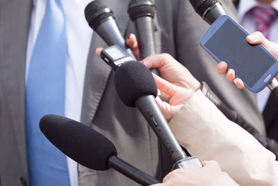 Cropped hand of journalist holding microphone in front of businessman