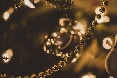 Close up of beads, ornaments and lights on a christmas tree.