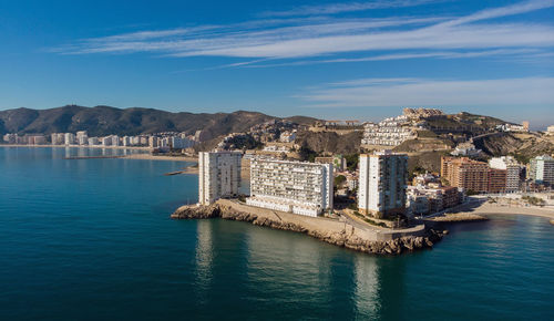 Sea by city buildings against sky