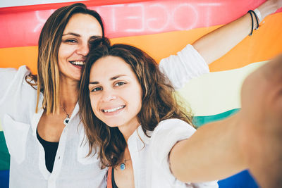 Portrait of smiling lesbians with rainbow flag