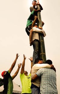 Rear view of people with arms raised against sky