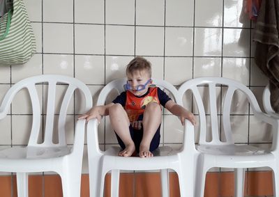 Full length of boy sitting on chair at home