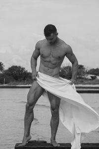 Portrait of shirtless man standing at beach