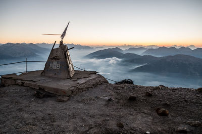 Traditional windmill on mountain against sky during sunset