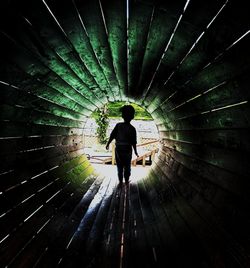 Rear view of man walking in tunnel