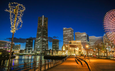 Illuminated buildings in city against clear sky at night