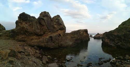 Rock formations by sea against sky