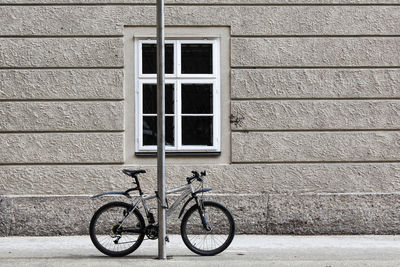Bicycle parking by pole against building