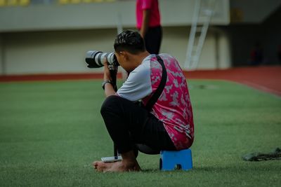 Side view of man photographing with camera