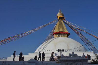 Group of people in front of building against blue sky