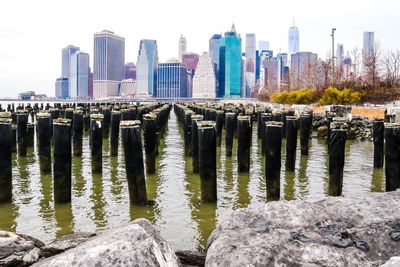 Wooden posts in east river against modern buildings at manhattan