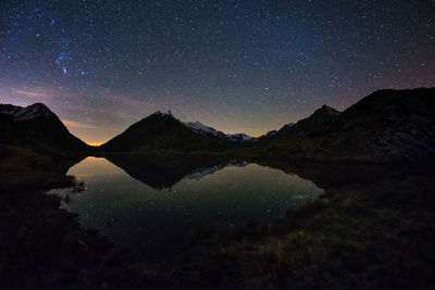 Scenic view of lake and mountains against sky at night