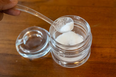 Cropped image of person taking salt from jar on table