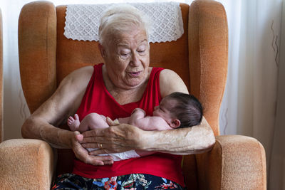 Grandmother holding her newborn baby granddaughter at home