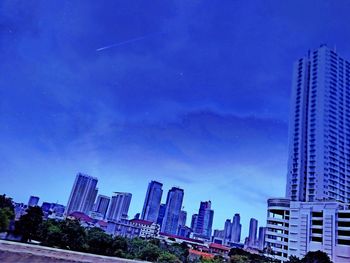 Low angle view of skyscrapers against blue sky