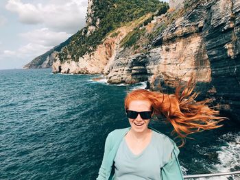 Portrait of cheerful woman against sea