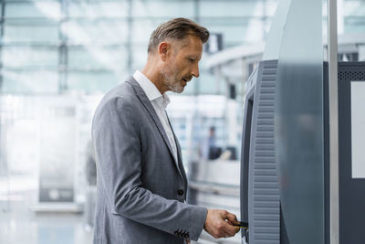 Mature businessman inserting credit card in atm machine