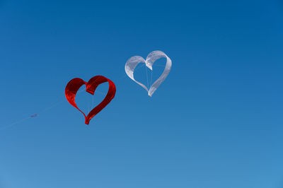 Low angle view of heart shape kite against blue sky