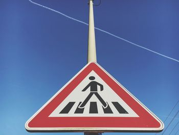 Low angle view of sign board against clear blue sky