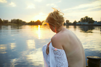 Rear view of woman standing in lake against sky