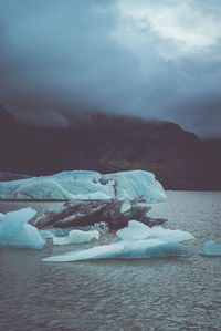 Scenic view of glaciers in sea against mountains