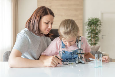 Mother helping daughter in science project at home