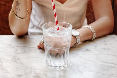 Midsection of woman with drink on table in restaurant