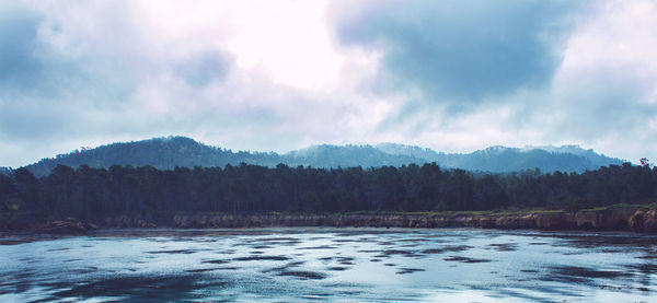 Scenic view of river by mountains against sky